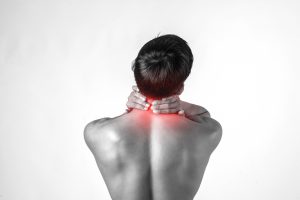 Muscular man use handles at the neck to relieve pain isolated on